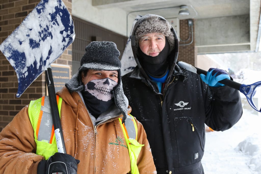 (BASIL JOHN / THE STATESMAN) Andrew Rosenbluth and Michael Rogers, above, who work for a private snow-removal company, pose for a photo with their shovels outside of the Staller Center for the Arts during the aftermath of Winter Storm Juno on Monday, Jan. 26.