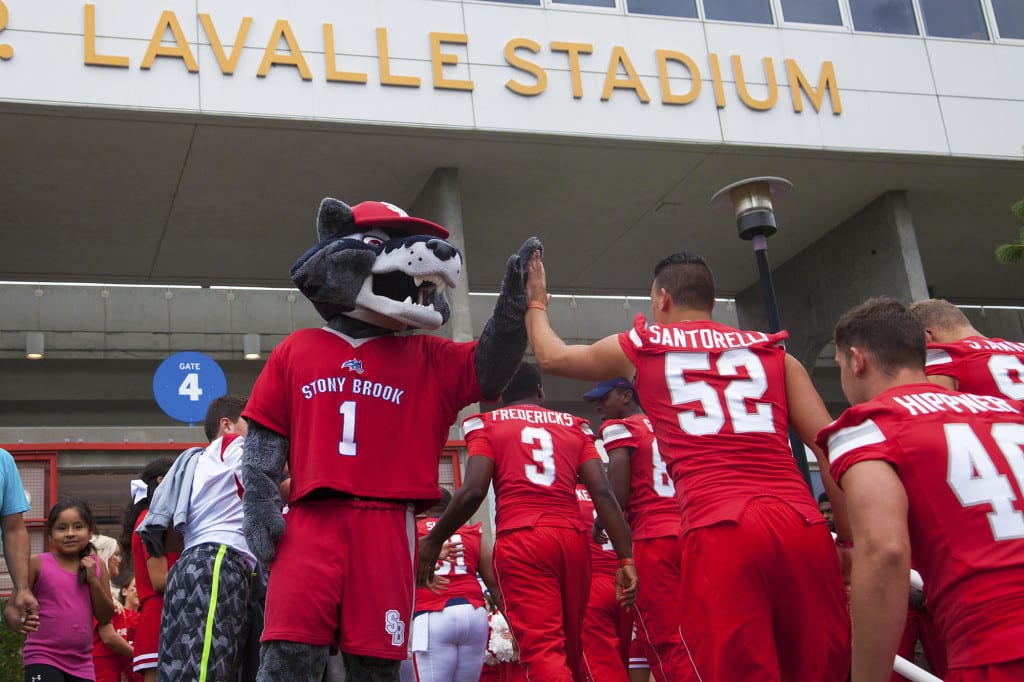 Wolfie high-fiving the Stony Brook Seawolves as they enter Kenneth P. LaValle stadium for a game in 2015. Various students groups on campus are calling to remove Senator Lavalles name from the stadium. GISELLE MIRANDA/STATESMAN FILE
