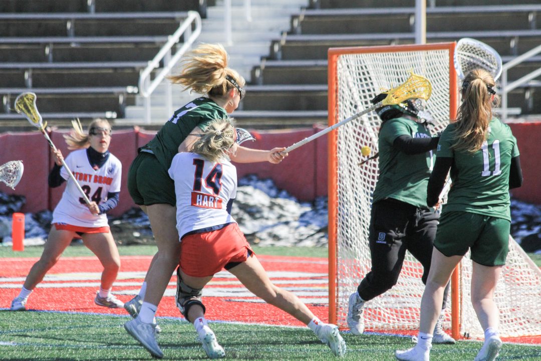 Attacker Kailyn Hart colliding into opposing Dartmouth player while scoring a goal during the game on 
Feb 27. The Seawolves dominated the game against Darthmouth winning their first game of the season 20-3.  KAT PROCACCI/THE STATESMAN