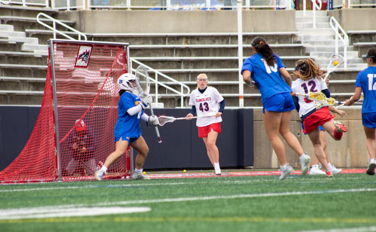 Attacker Alex Finn (43) looks on as midfielder Ellie Masera (12) prepares to take a behind-the-back shot against Hofstra on Sunday, April 21. Masera and Finn co-led the Stony Brook womens lacrosse team with seven points each during its CAA-clinching victory. BRITTNEY DIETZ/THE STATESMAN